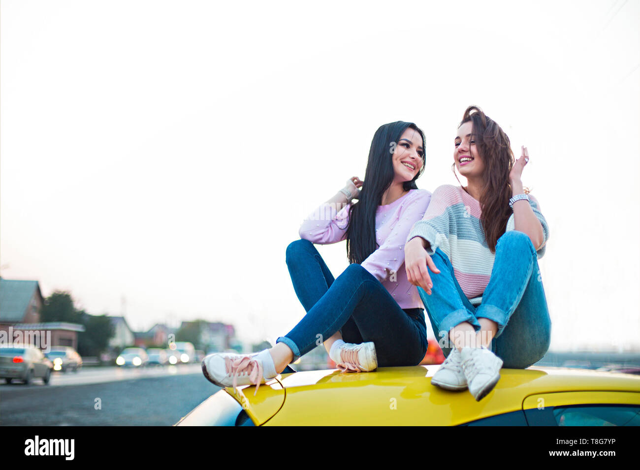 Best female friends cheering by car road trip at sunset. Happy people outdoor on vacation tour.  Friendship concept at travel with positive nostalgic  Stock Photo