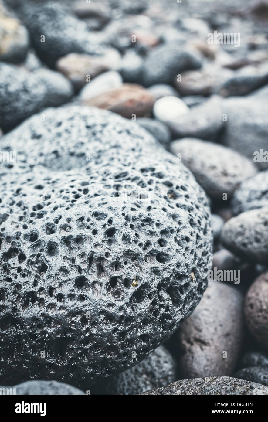 Close up picture of a volcanic rock on a beach, selective focus, color toning applied. Stock Photo