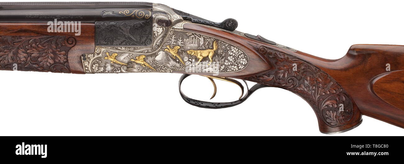 An deluxe over-and-under shotgun Heym mod. 212 SS Cal. 12/70, no. 48455. German proof mark 1970. Mirror-like bores, length 73 cm. Ventilated rib. Barrel root with inlaid gold thread, engraved with oak leaves and winged game. Left hand-side: pheasant. Right hand-side: duck. Kersten lock. Side locks. Action completely engraved with oak leaves. Additional hunting scenes on long side plates. Left hand-side: hound and flushing pheasants. Gold inlays. Right hand-side: fox and flushing geese. Gold inlays. On underside: hare as gold inlay. Trigger guard , Additional-Rights-Clearance-Info-Not-Available Stock Photo