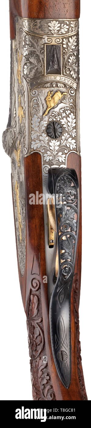 An deluxe over-and-under shotgun Heym mod. 212 SS Cal. 12/70, no. 48455. German proof mark 1970. Mirror-like bores, length 73 cm. Ventilated rib. Barrel root with inlaid gold thread, engraved with oak leaves and winged game. Left hand-side: pheasant. Right hand-side: duck. Kersten lock. Side locks. Action completely engraved with oak leaves. Additional hunting scenes on long side plates. Left hand-side: hound and flushing pheasants. Gold inlays. Right hand-side: fox and flushing geese. Gold inlays. On underside: hare as gold inlay. Trigger guard , Additional-Rights-Clearance-Info-Not-Available Stock Photo