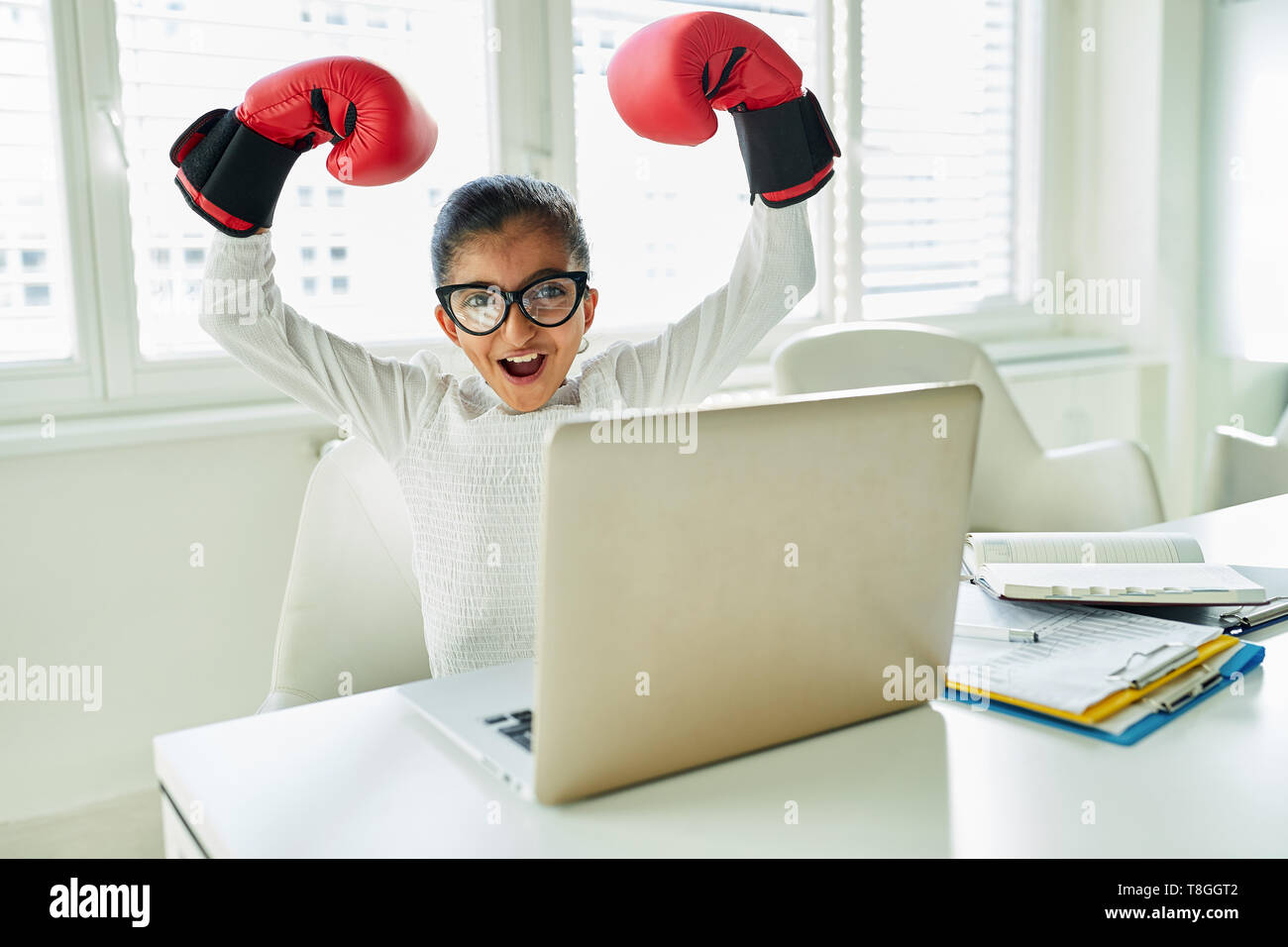 Cheering girl with boxing gloves in business start-up on laptop computer Stock Photo