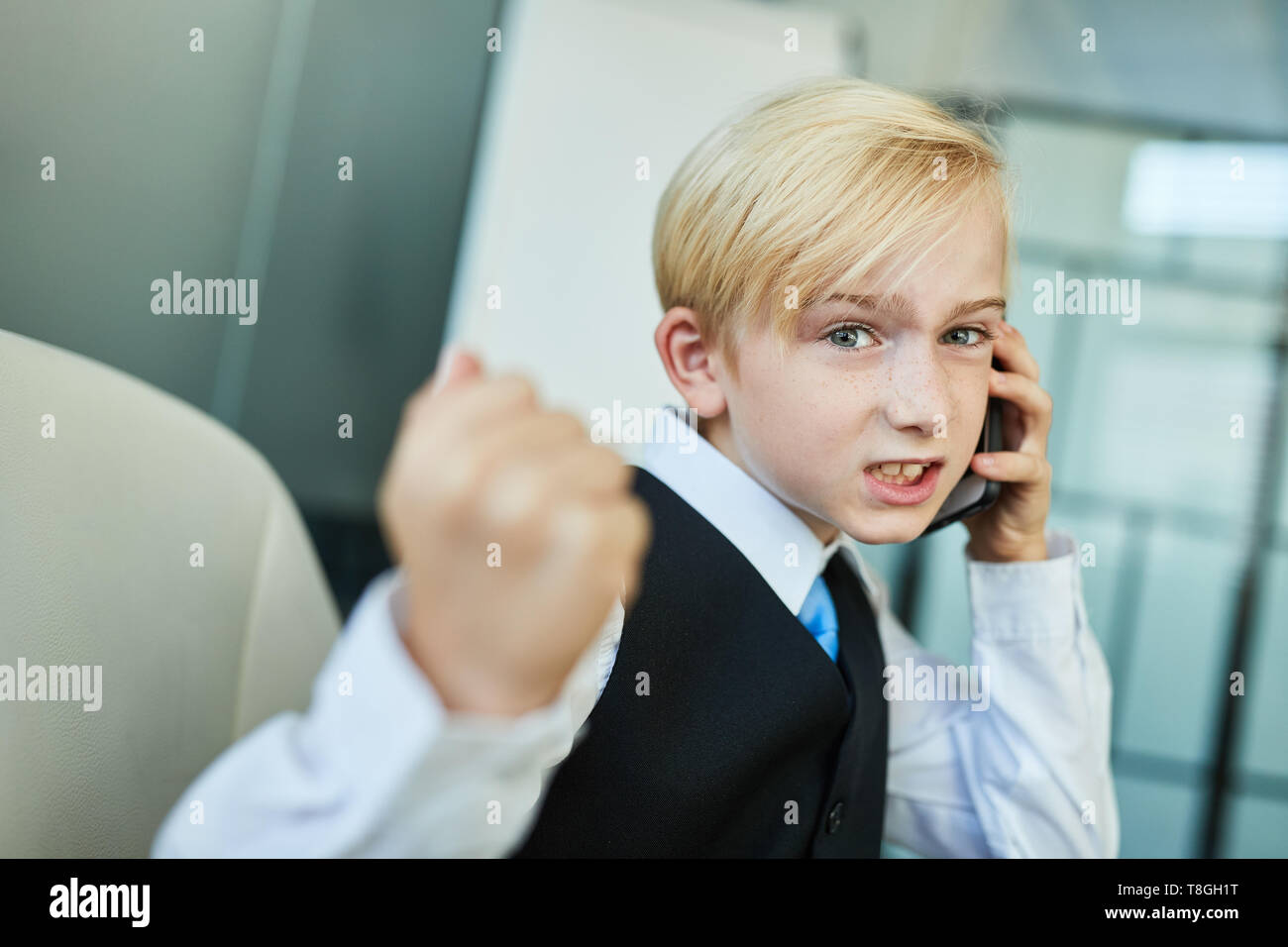 Child as a manager talking on the phone with his smartphone in the office Stock Photo