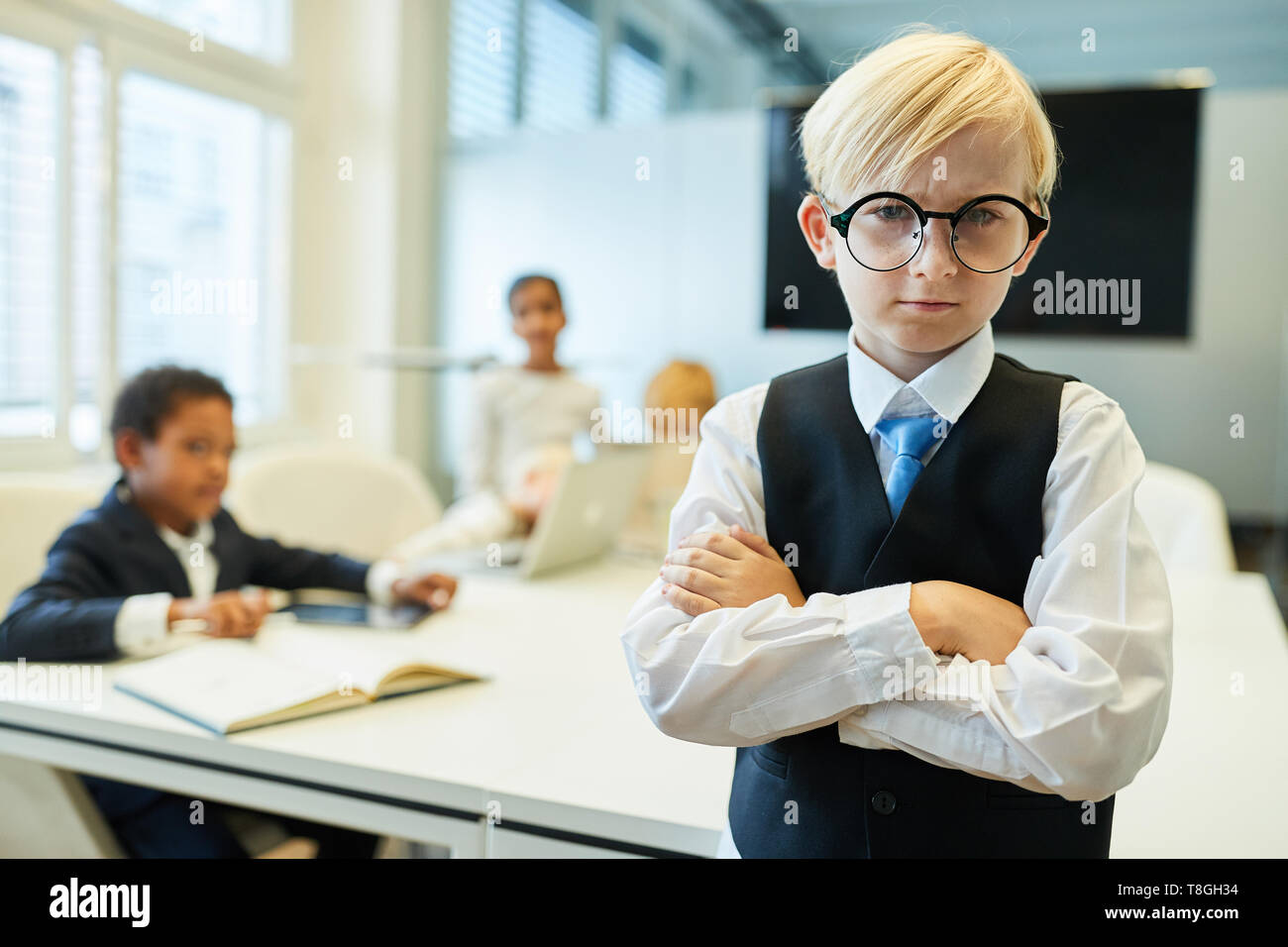 Boy as a critical manager or entrepreneur with arms crossed in a meeting Stock Photo