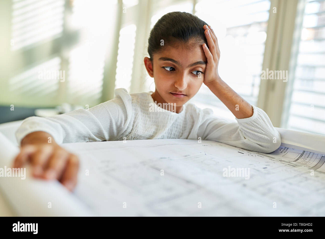 African child as an architect looks thoughtfully at a drawing Stock Photo