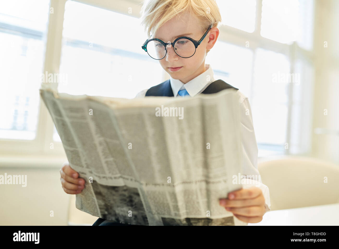 Boy as a businessman reads newspaper as a concept for print media and press freedom Stock Photo