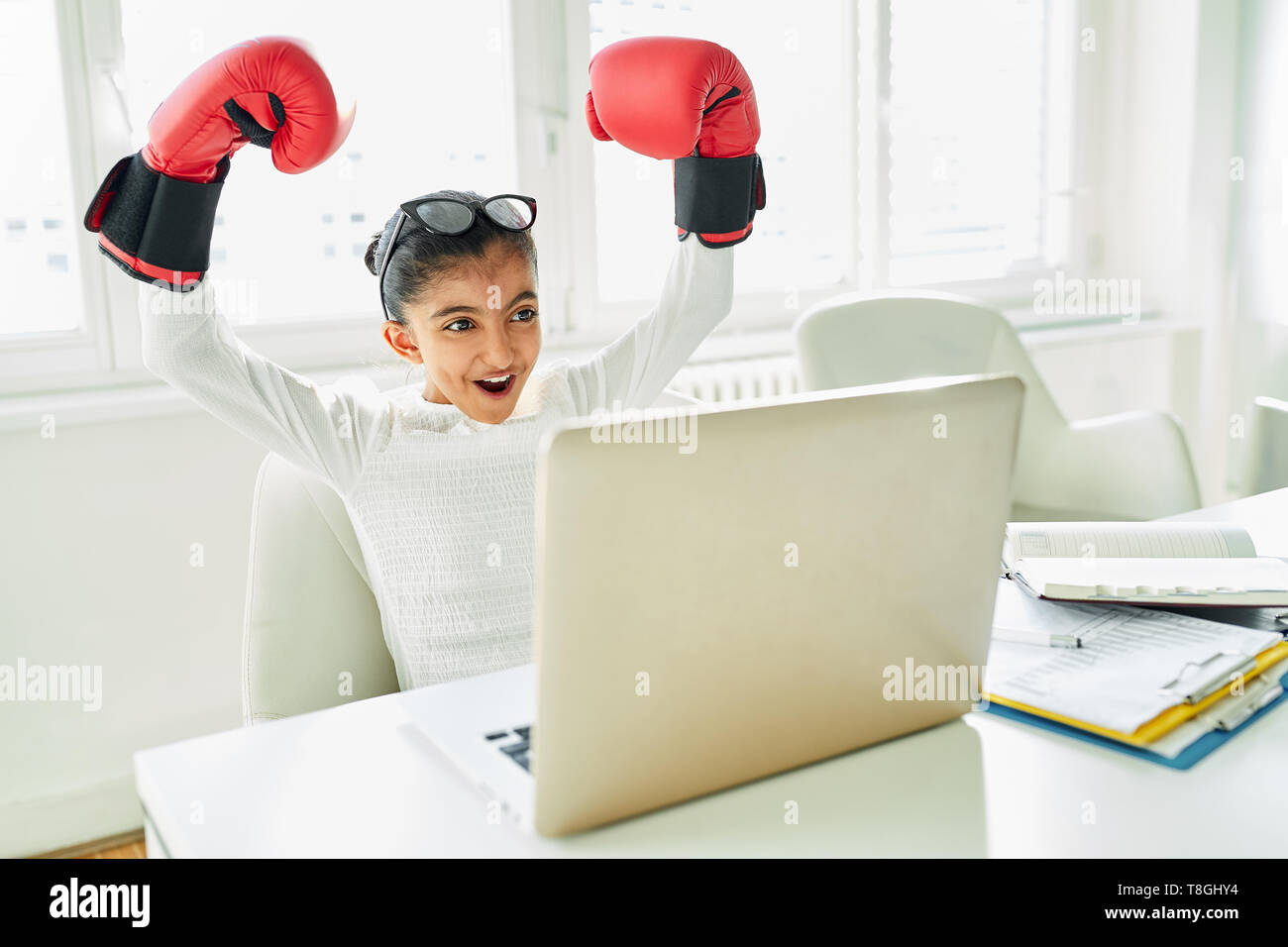 Girl with Boxing Gloves on Laptop Computer Cheers about a Success Stock Photo