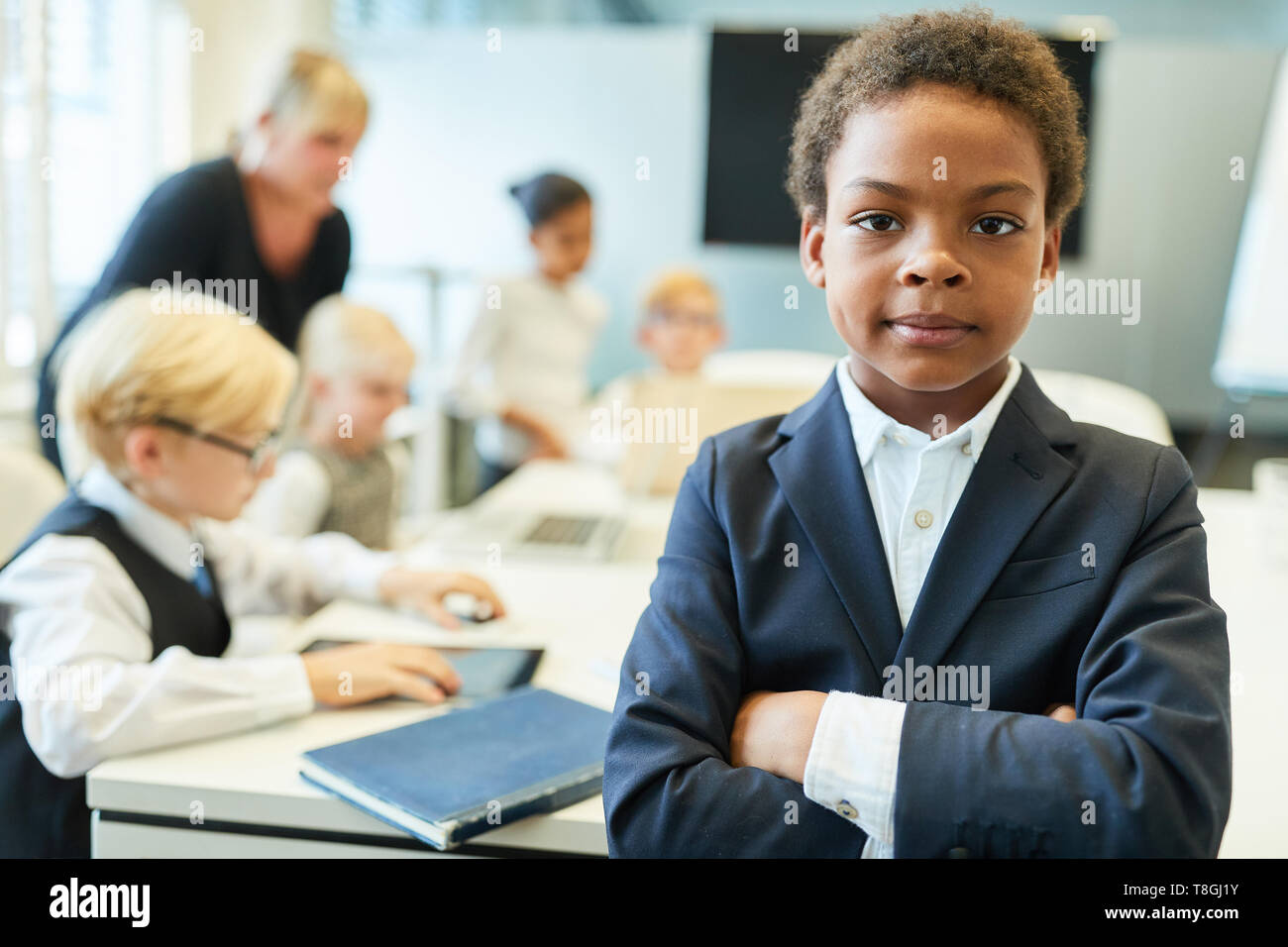 African child with crossed arms as a manager in front of a kids business team Stock Photo