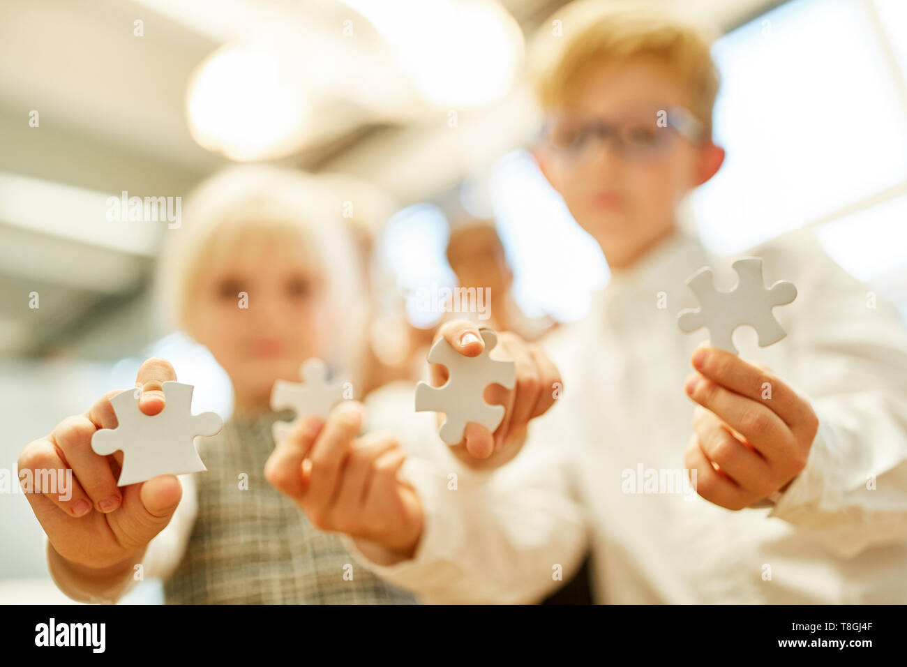 Children show different puzzle pieces as a sign of challenge and patience Stock Photo