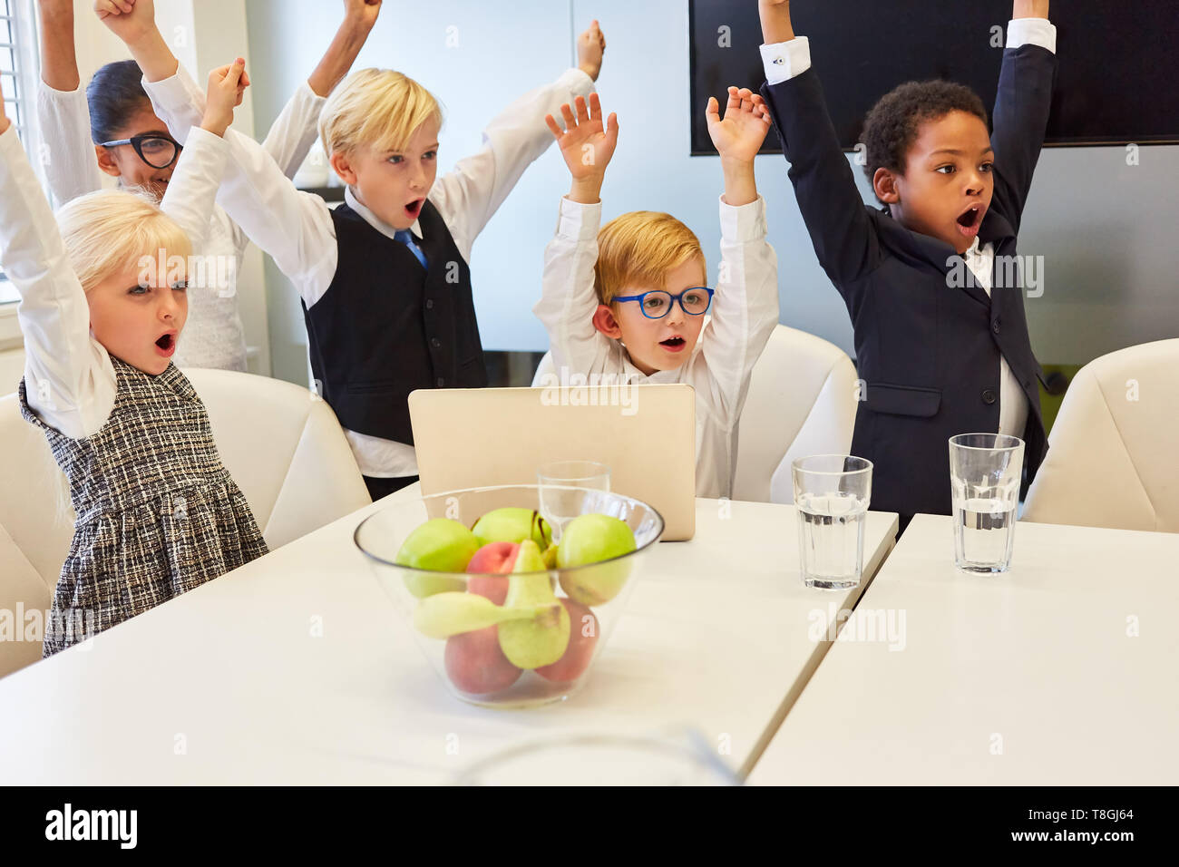 Cheering business kids team with laptop computer celebrating a success Stock Photo