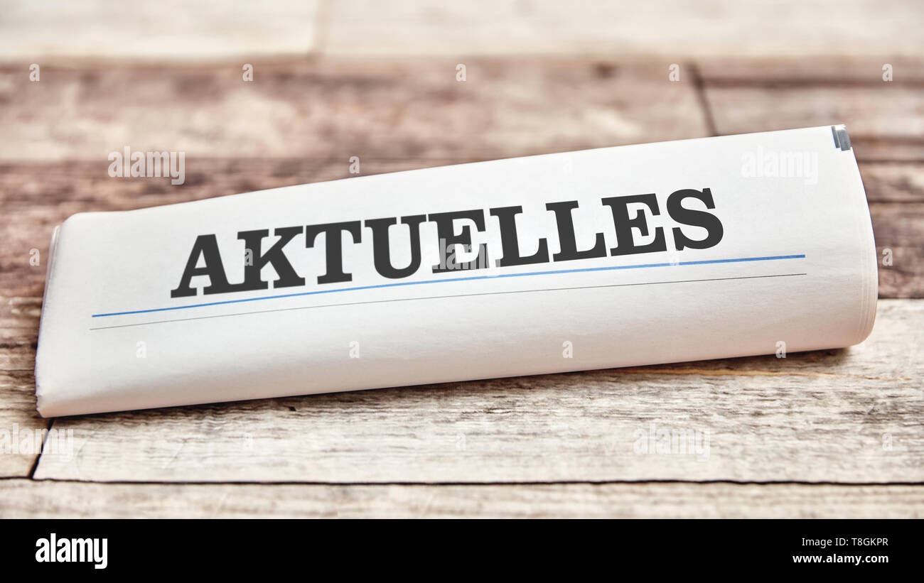 German word 'Aktuelles' (News) on newspaper or newsletter on a wooden table Stock Photo