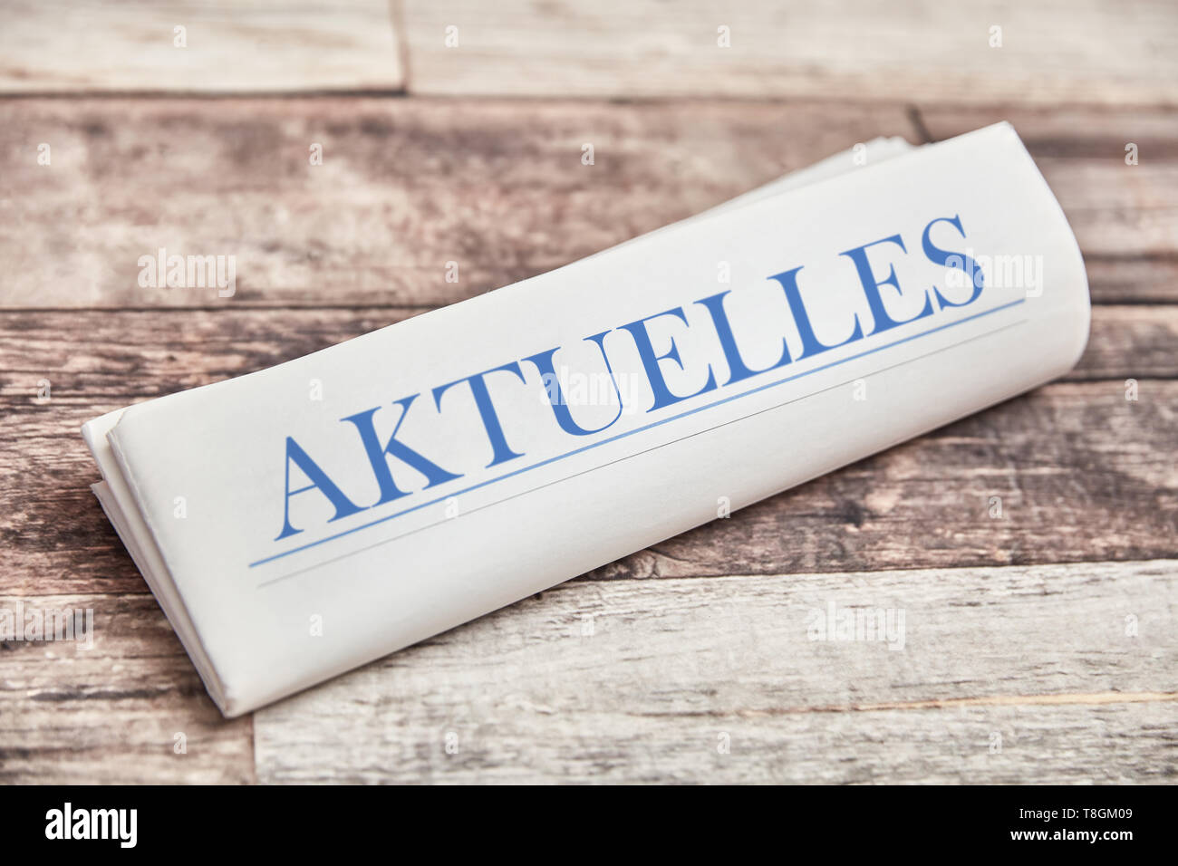 German word 'Aktuelles' (news) in newspaper on wood Stock Photo
