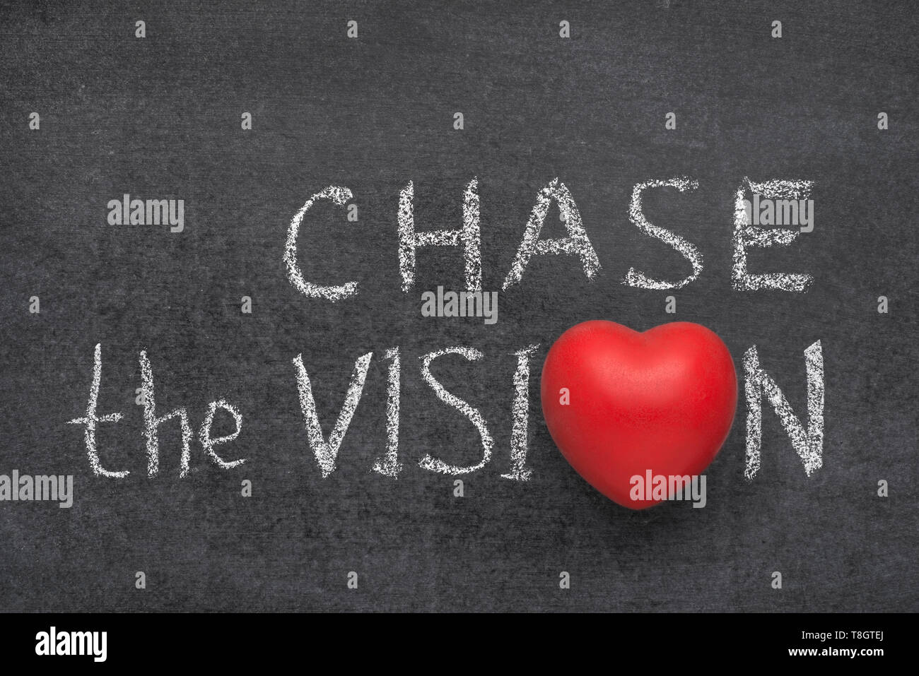 chase the vision phrase handwritten on blackboard with heart symbol instead of O Stock Photo