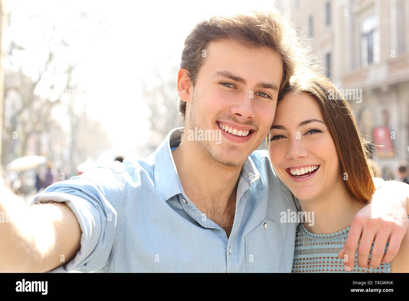 Happy couple are taking selfies in the street on summer holiday in a big city Stock Photo