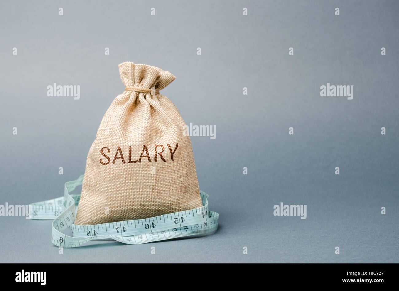 Money bag with the word Salary and tape measure. Wage cuts. The concept of limited profit. Lack of money and poverty. Small income. Salary reduction. Stock Photo