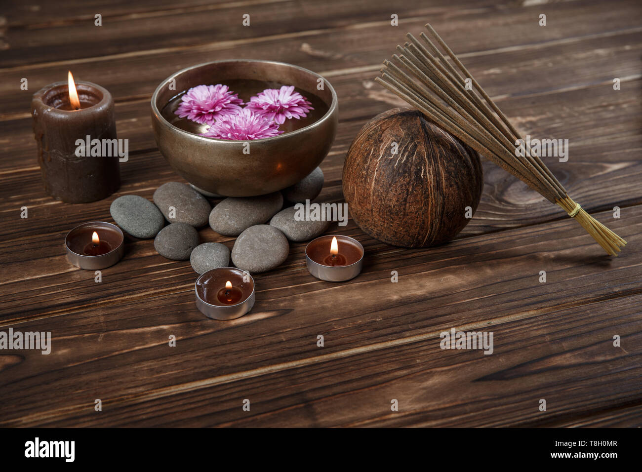 Singing bowl with candles with pebbles on dark wooden background with