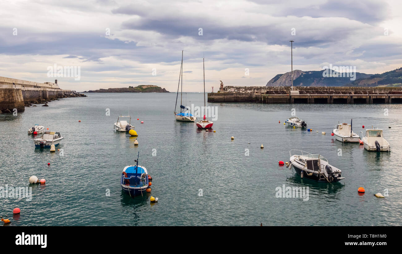 Small boats at the entrance of the fishing port of Bermeo on the coast of Vizcaya on a cloudy day, Spain Stock Photo