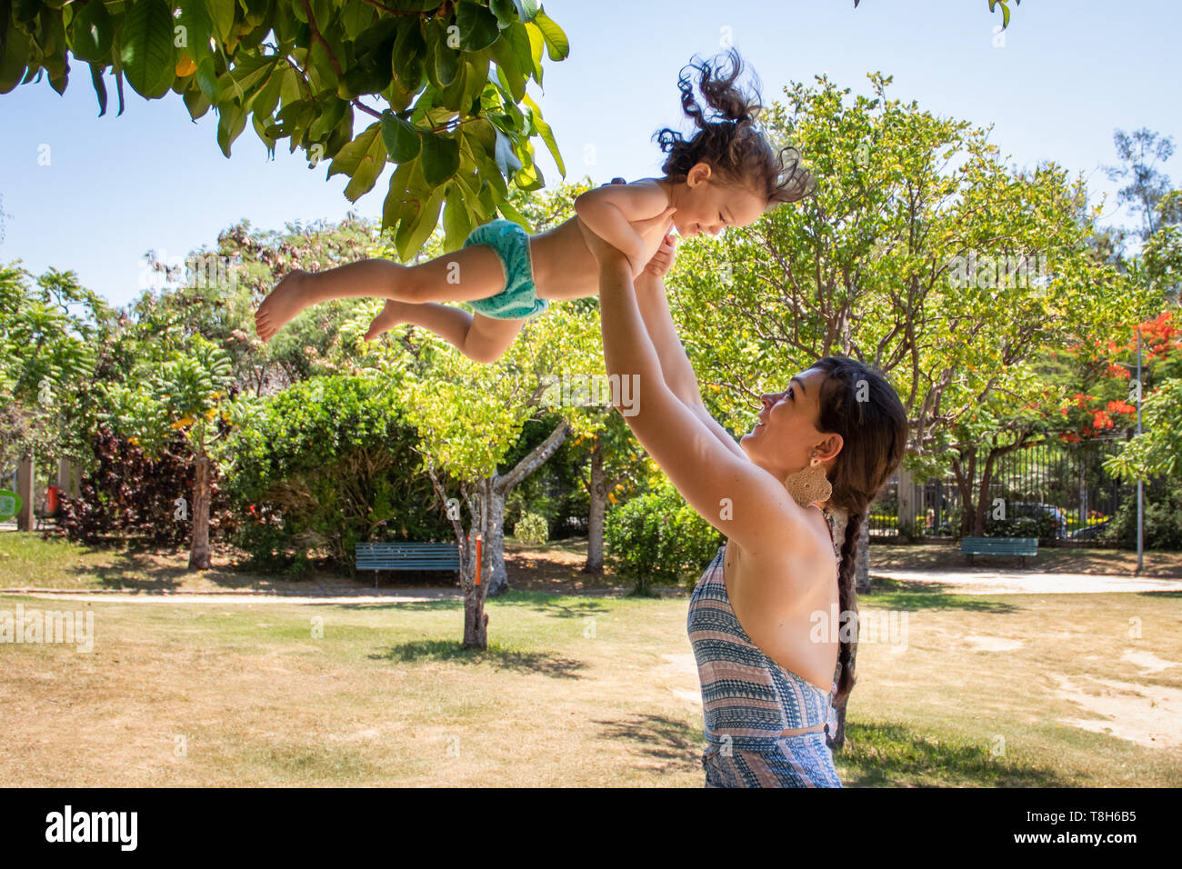 Woman standing in the park throwing her daughter in the air, Brazil Stock Photo