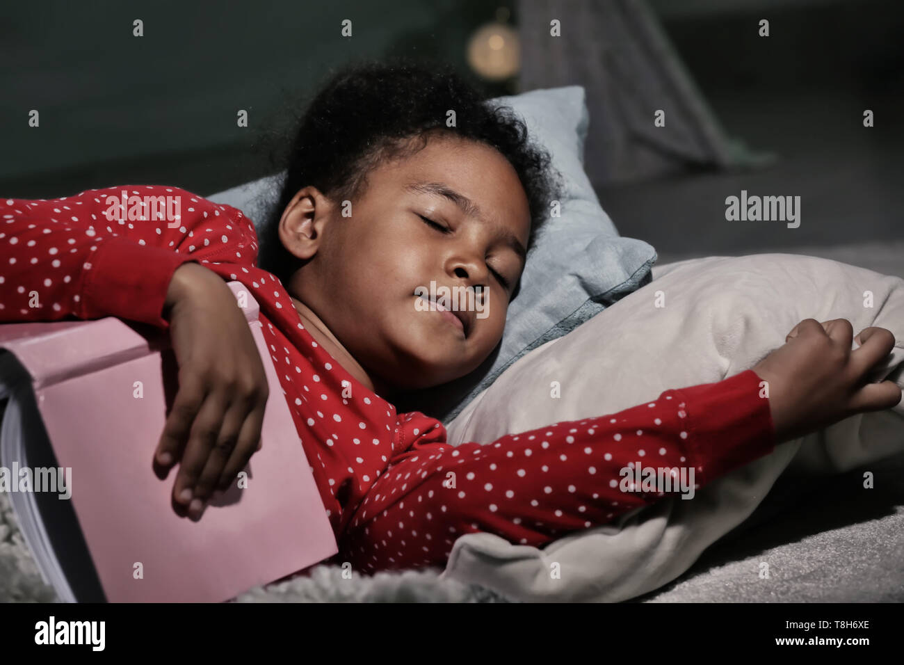 Little African-American girl with book sleeping in bed Stock Photo - Alamy