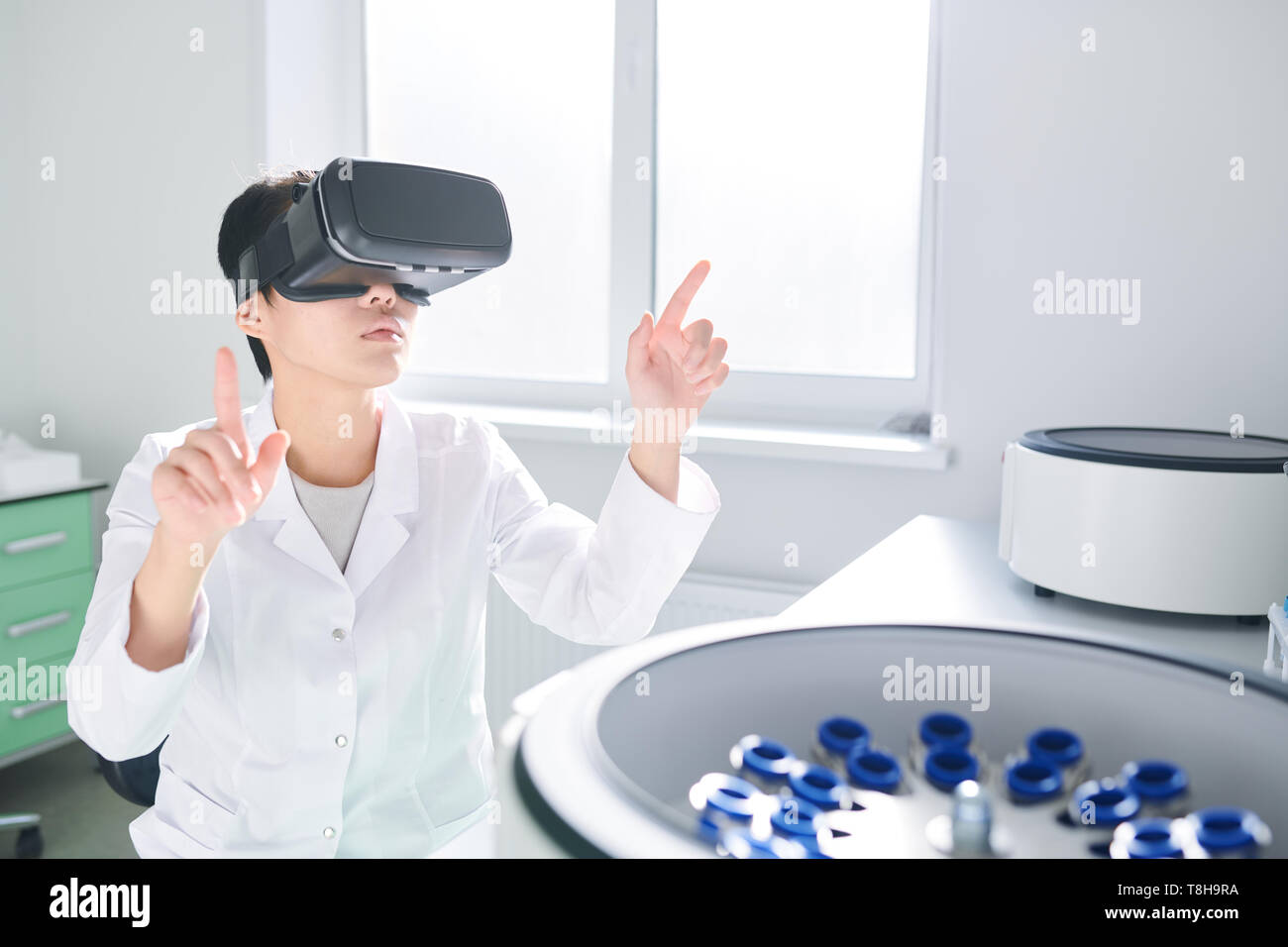 Laboratory technician synchronizing VR simulator with centrifuge  Stock Photo