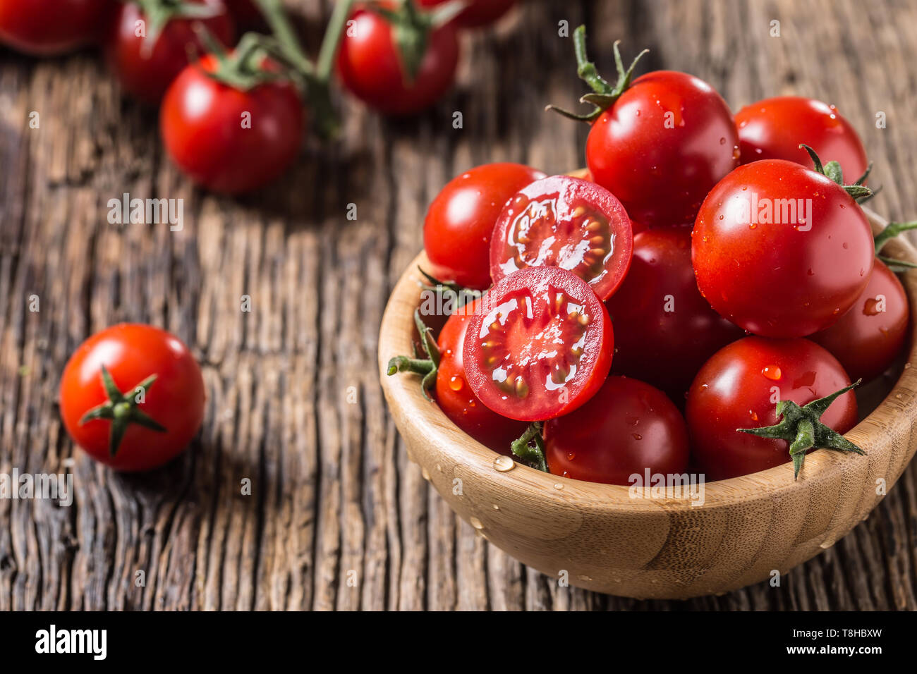 Fresh cherry tomatoes in wooden bowl on old oak table Stock Photo