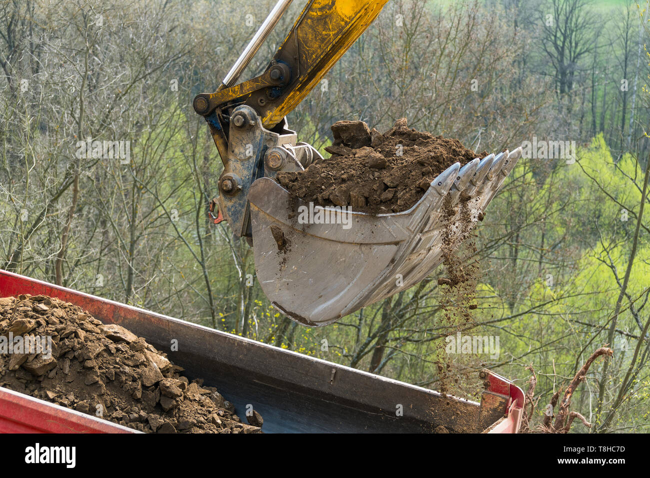 Working excavator shovel. Dump truck detail with soil pile. Building