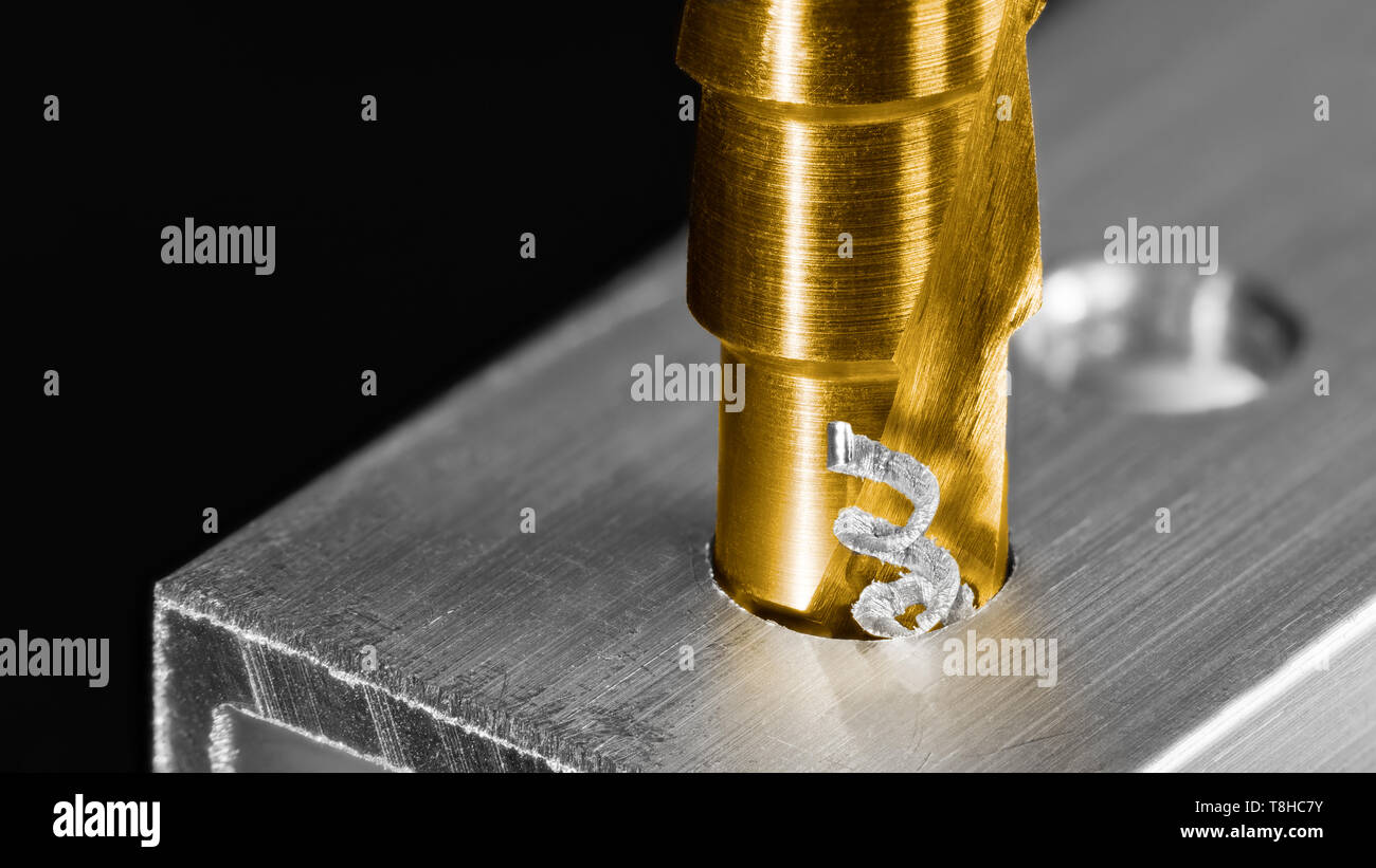 Step drill bit. Twisted swarf detail. Making hole in aluminum profile. Unibit closeup. Drilling of aluminium alloy by cutting tool coated by titanium. Stock Photo