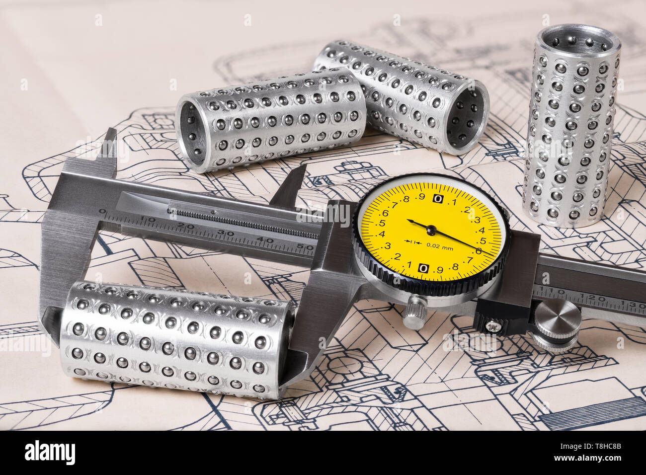 Linear ball bearings measurement. Caliper gauge. Technical drafting. Measuring of steel rollers and plan. Metallic vernier tool with round yellow dial. Stock Photo