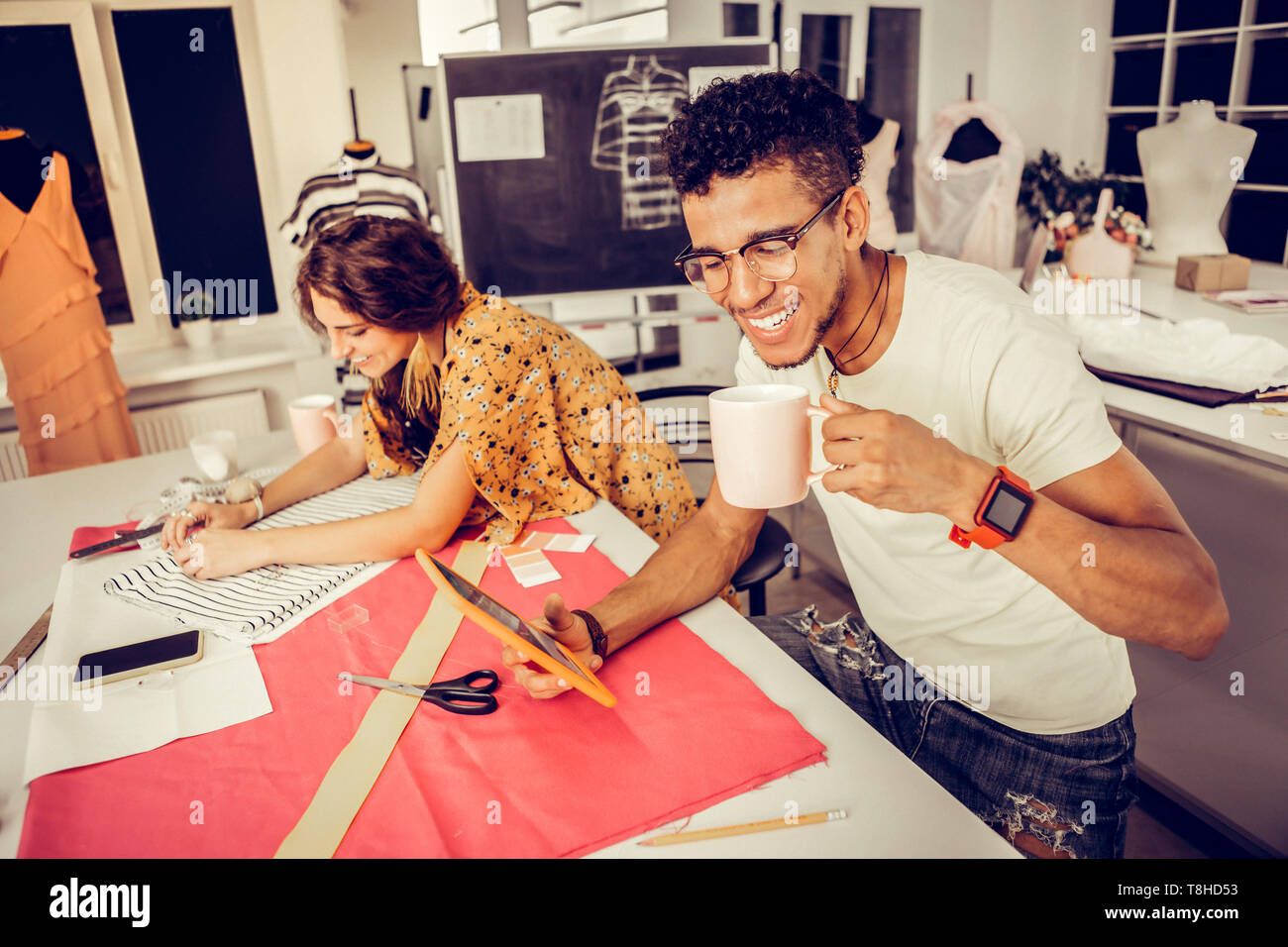 Joyful tailors working in a studio and laughing. Stock Photo
