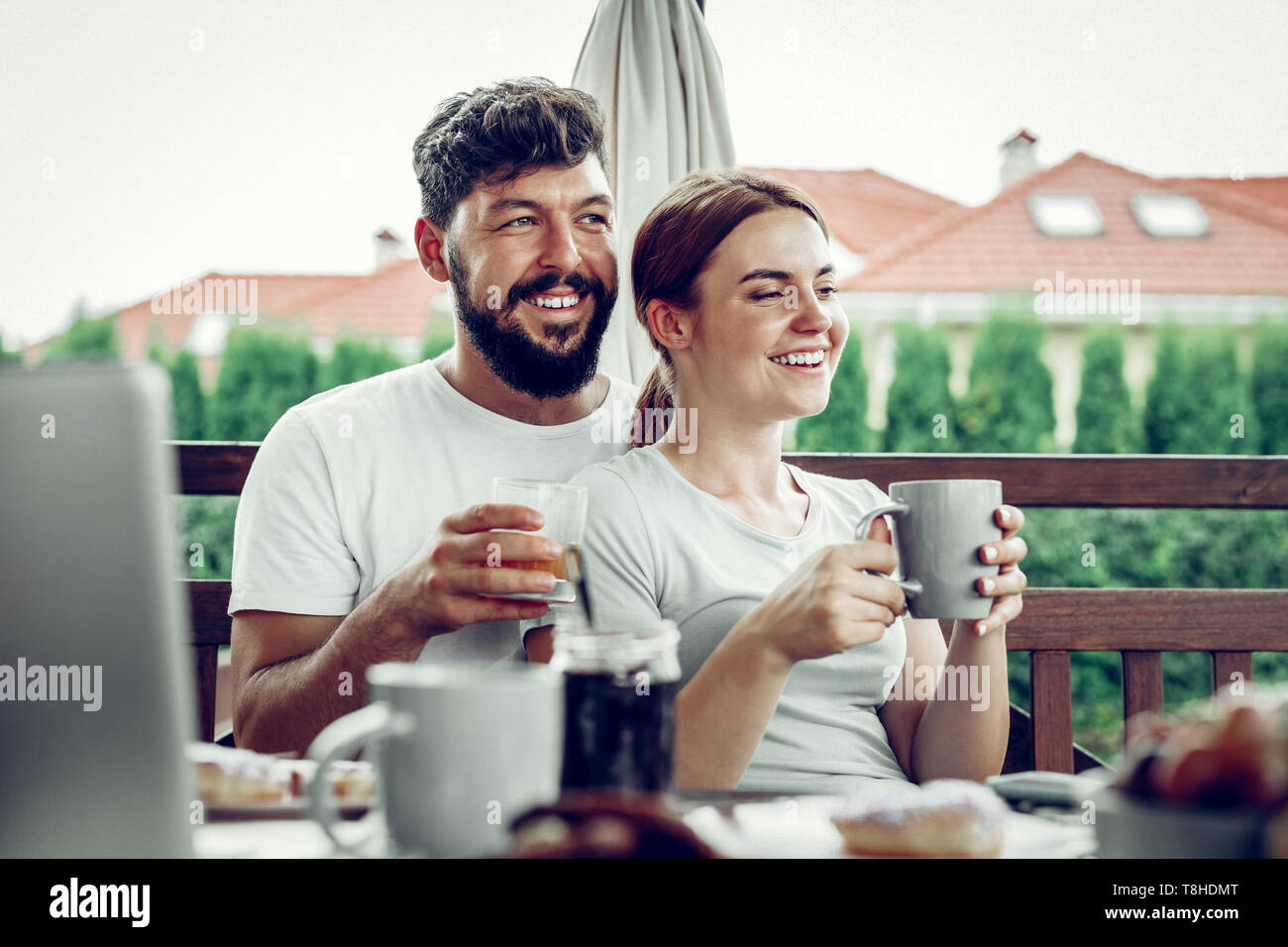 Happy husband embracing his spouse during breakfast in the garden. Stock Photo