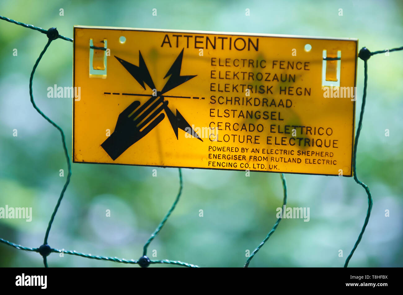 Electric fence warning sign in several different languages Stock Photo