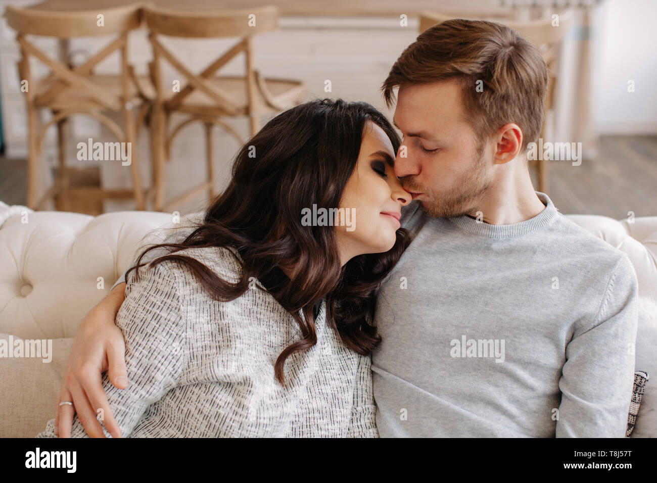 Happy couple sitting on a couch nuzzling Stock Photo