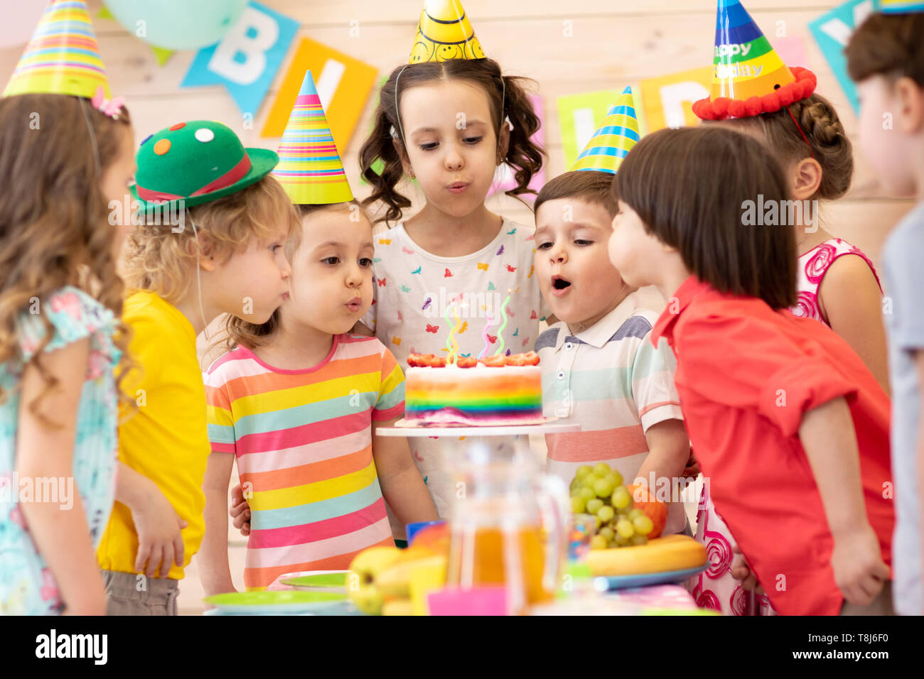Group of kids celebrating birthday party and blowing candles on cake ...