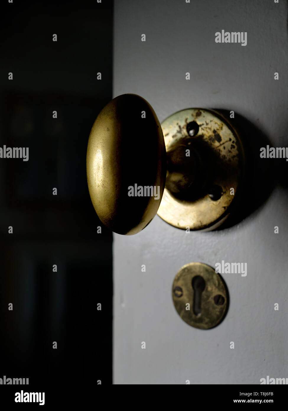 Close up of a brass door handle on an open old wooden door. Stock Photo