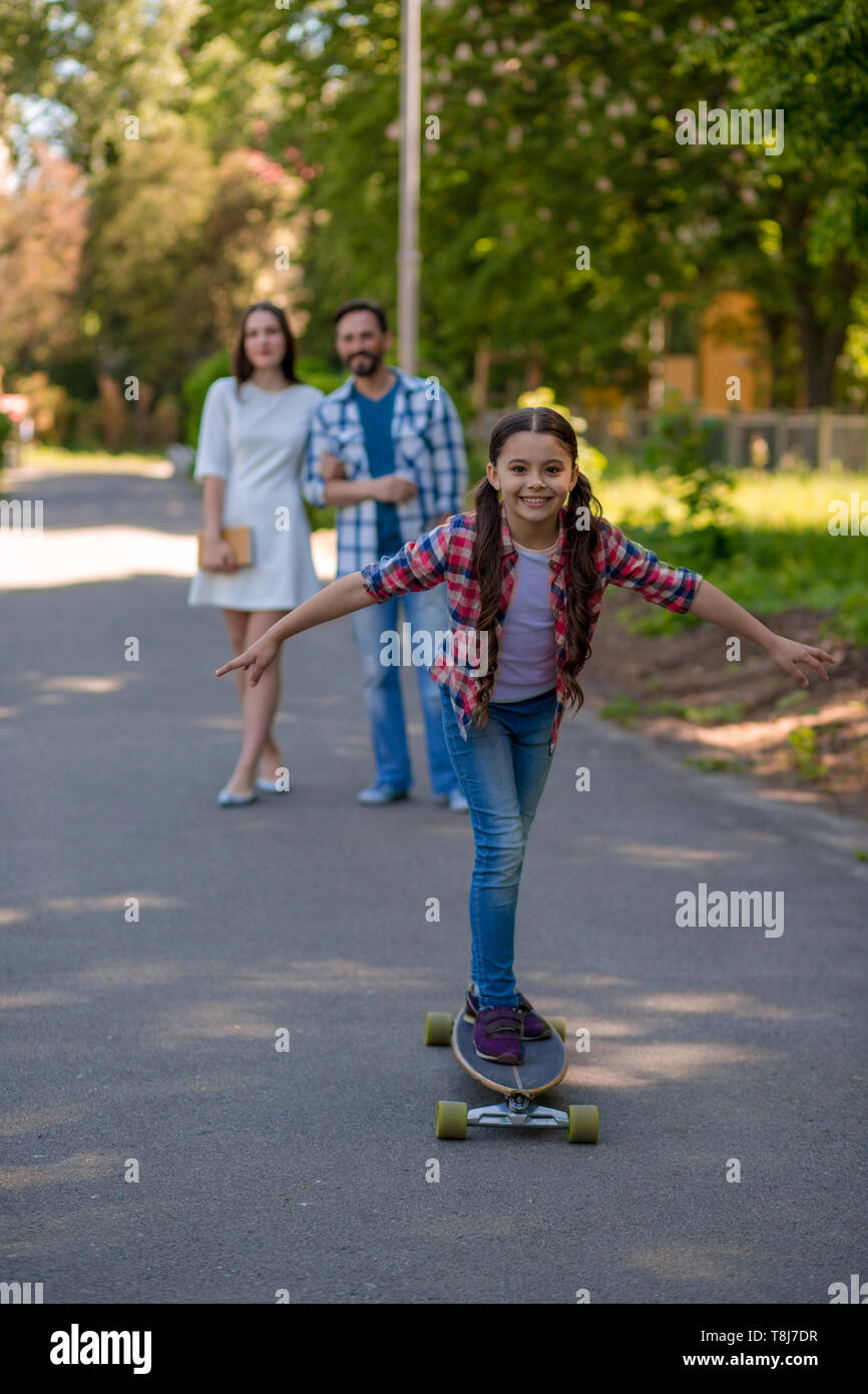 Smiling family with a skateboard in summer park Stock Photo