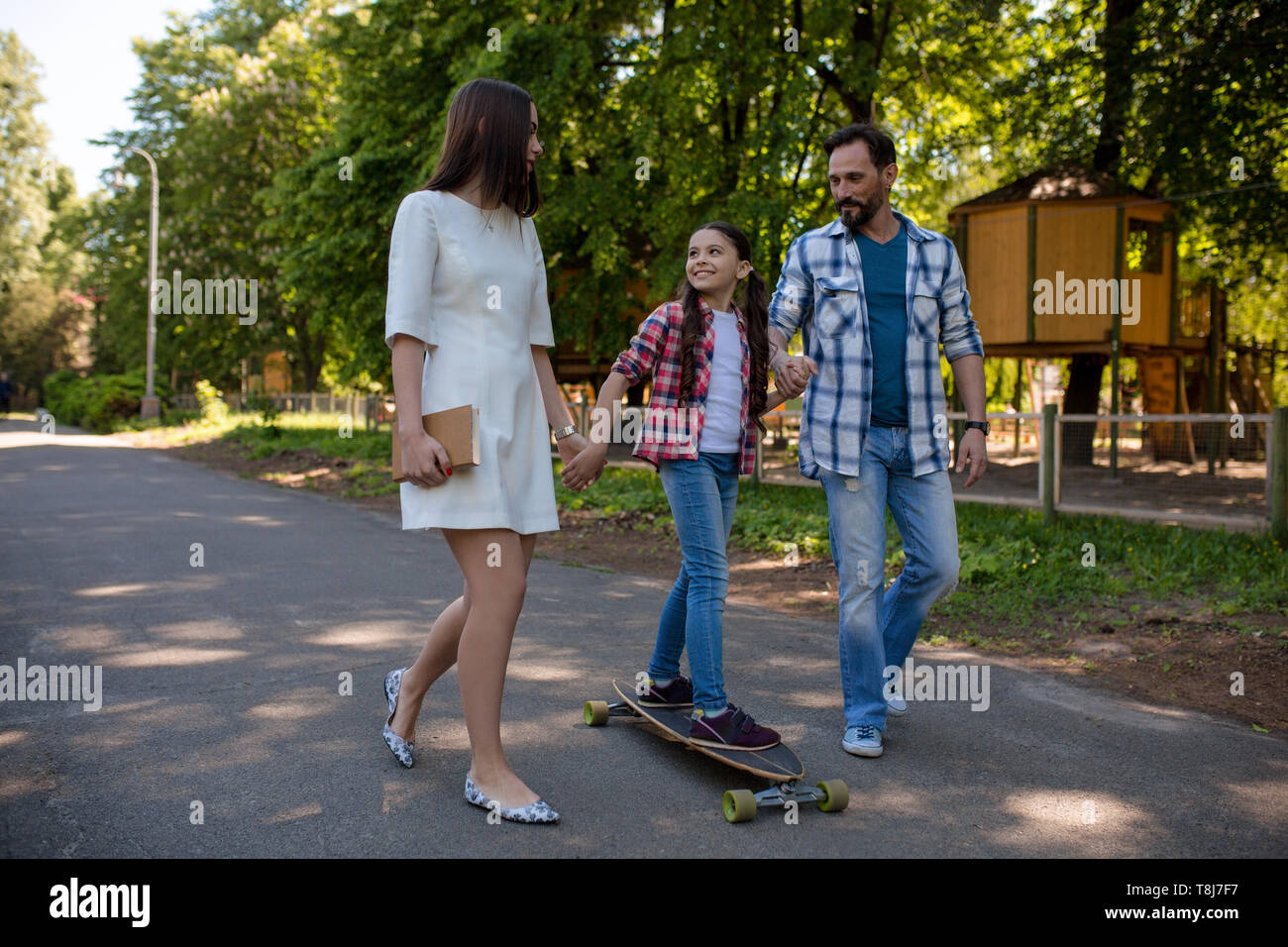 Smiling family with a skateboard in summer park Stock Photo