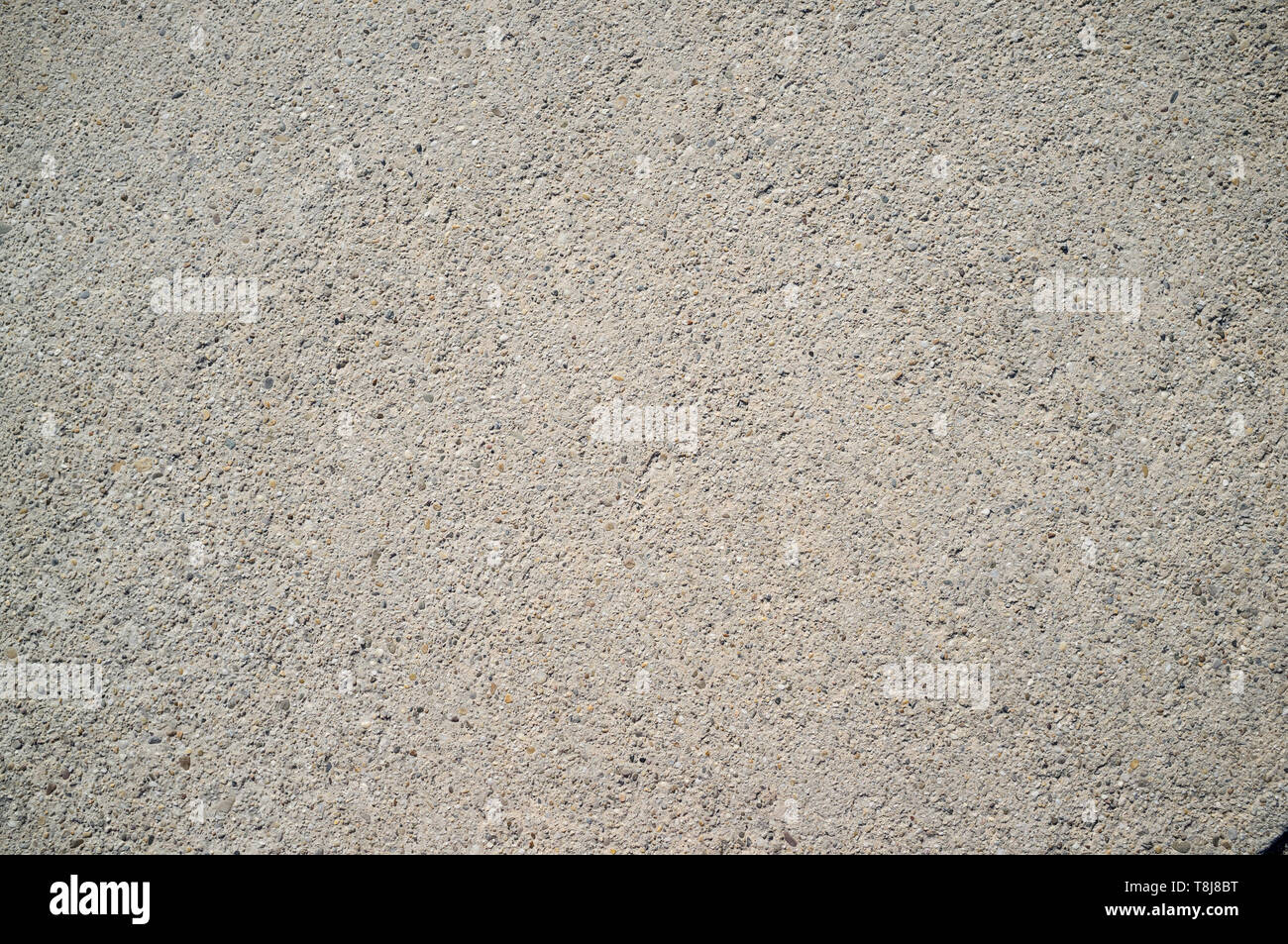 Texture of Old Weathered Concrete Wall with Small Rocks on Direct Sunlight Stock Photo