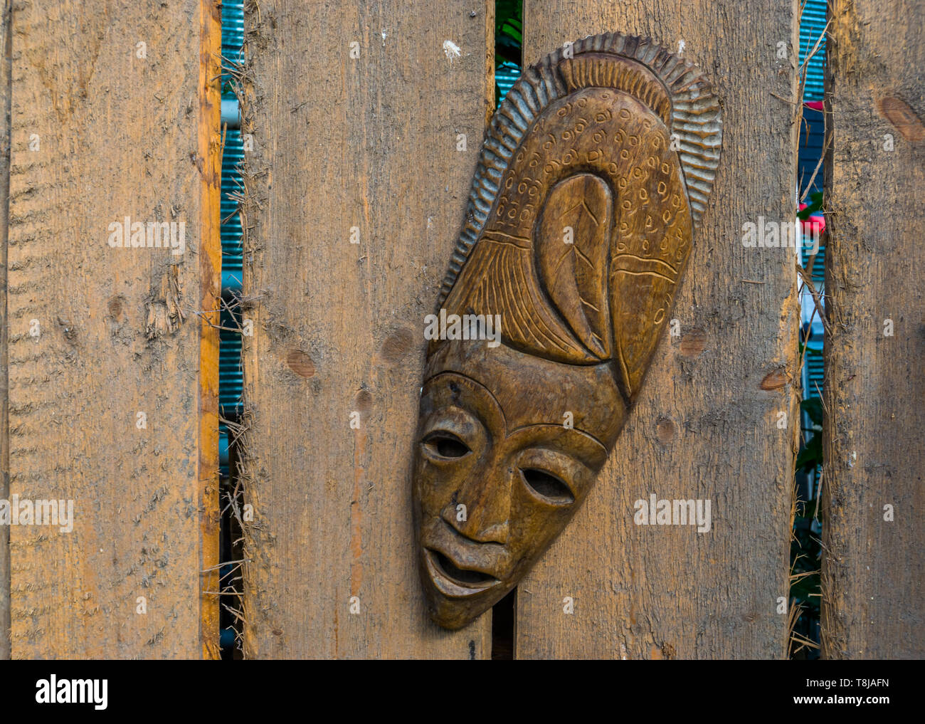traditional african mask hanging on a wooden fence, tropical garden