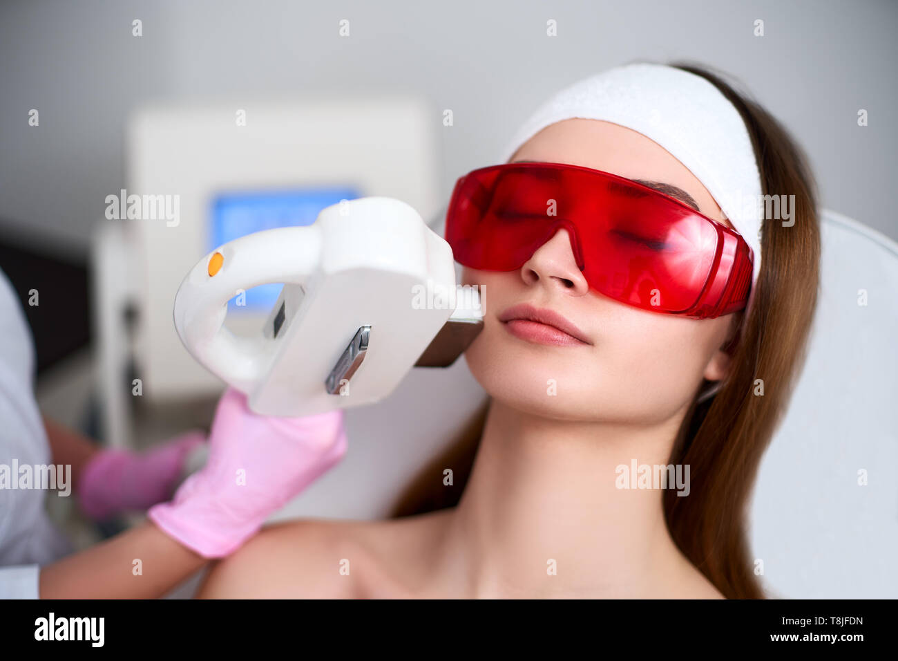 Beautician doctor doing laser RF-rejuvenation for attractive young woman at beauty salon. Elos cosmetological hair removal procedure. Aesthetic facial Stock Photo