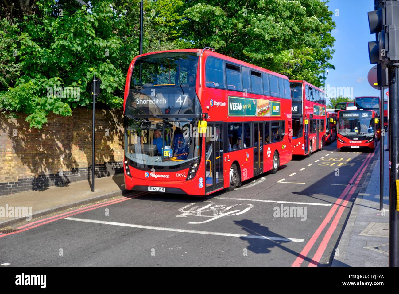 London, United Kingdom - May 13, 2019: Double decker buses line up at traffic lights waiting to leave Lewisham railway station Stock Photo