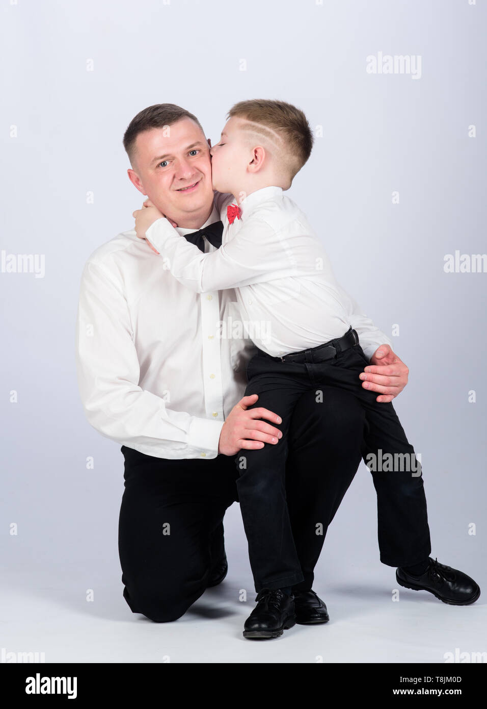 kid kiss his father. tuxedo style. little boy with dad businessman