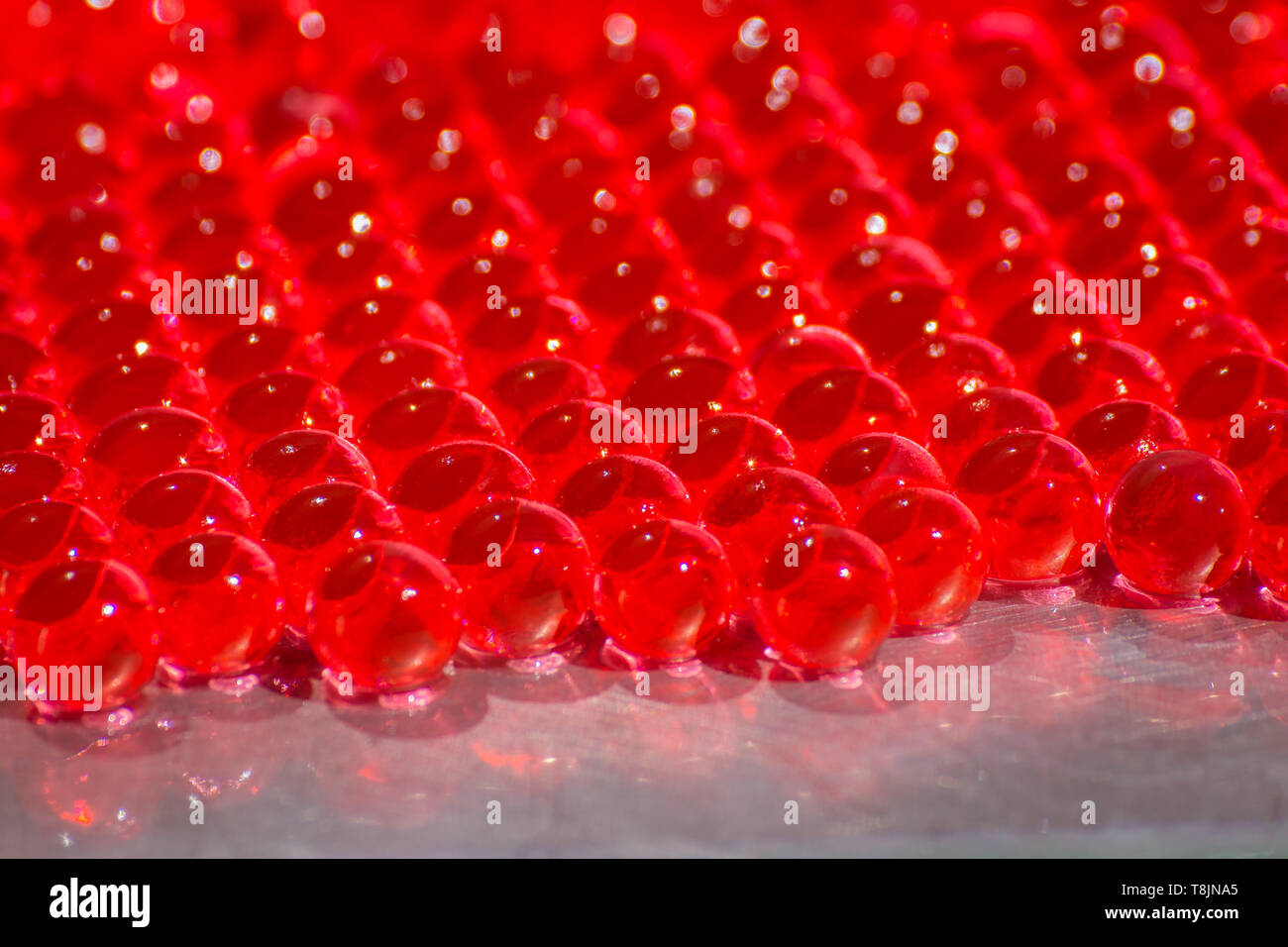 Water red gel balls with bokeh. Polymer gel. Silica gel. Balls of red
