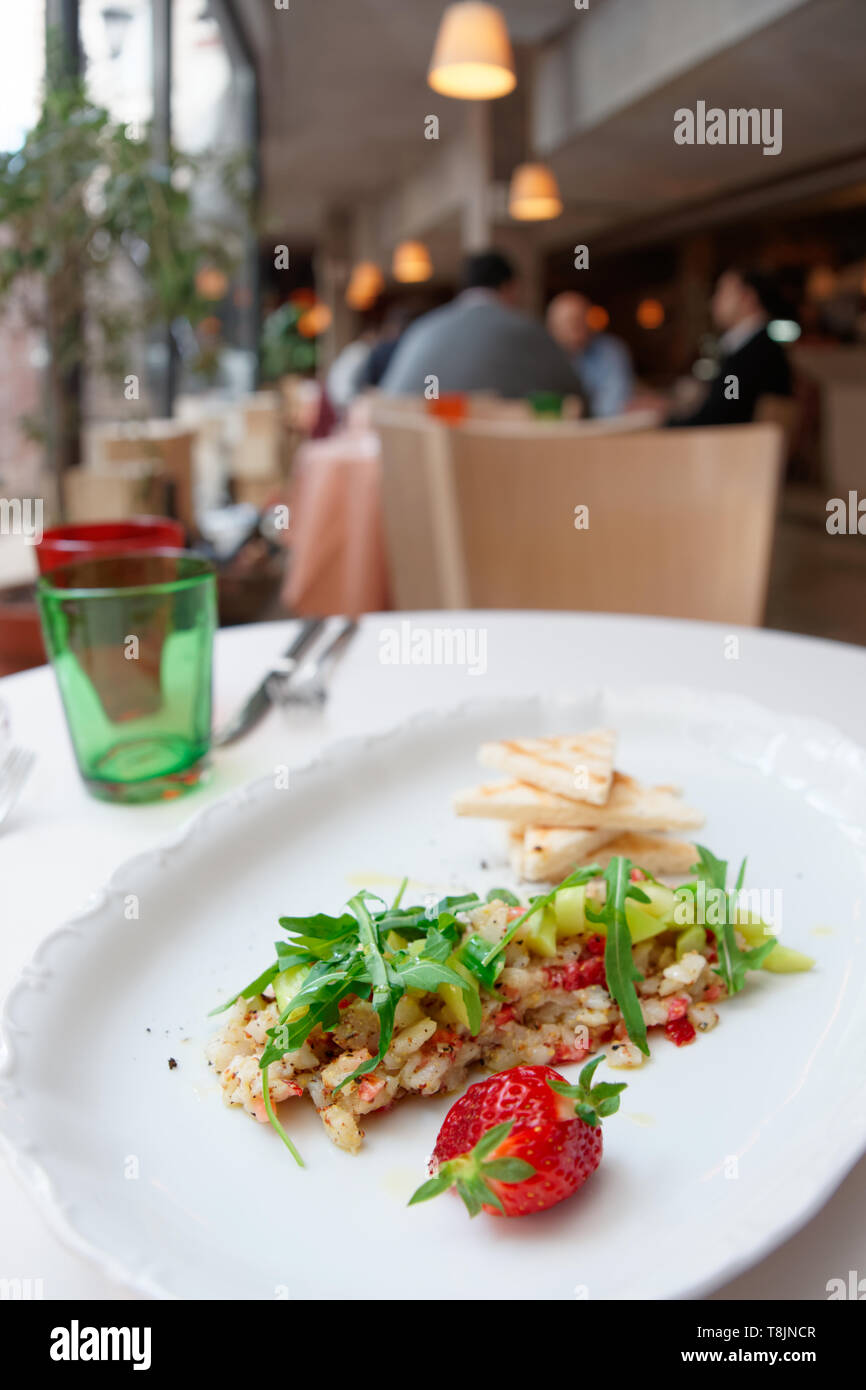 Seabass carpaccio on restaurant table, blurred people in background Stock Photo