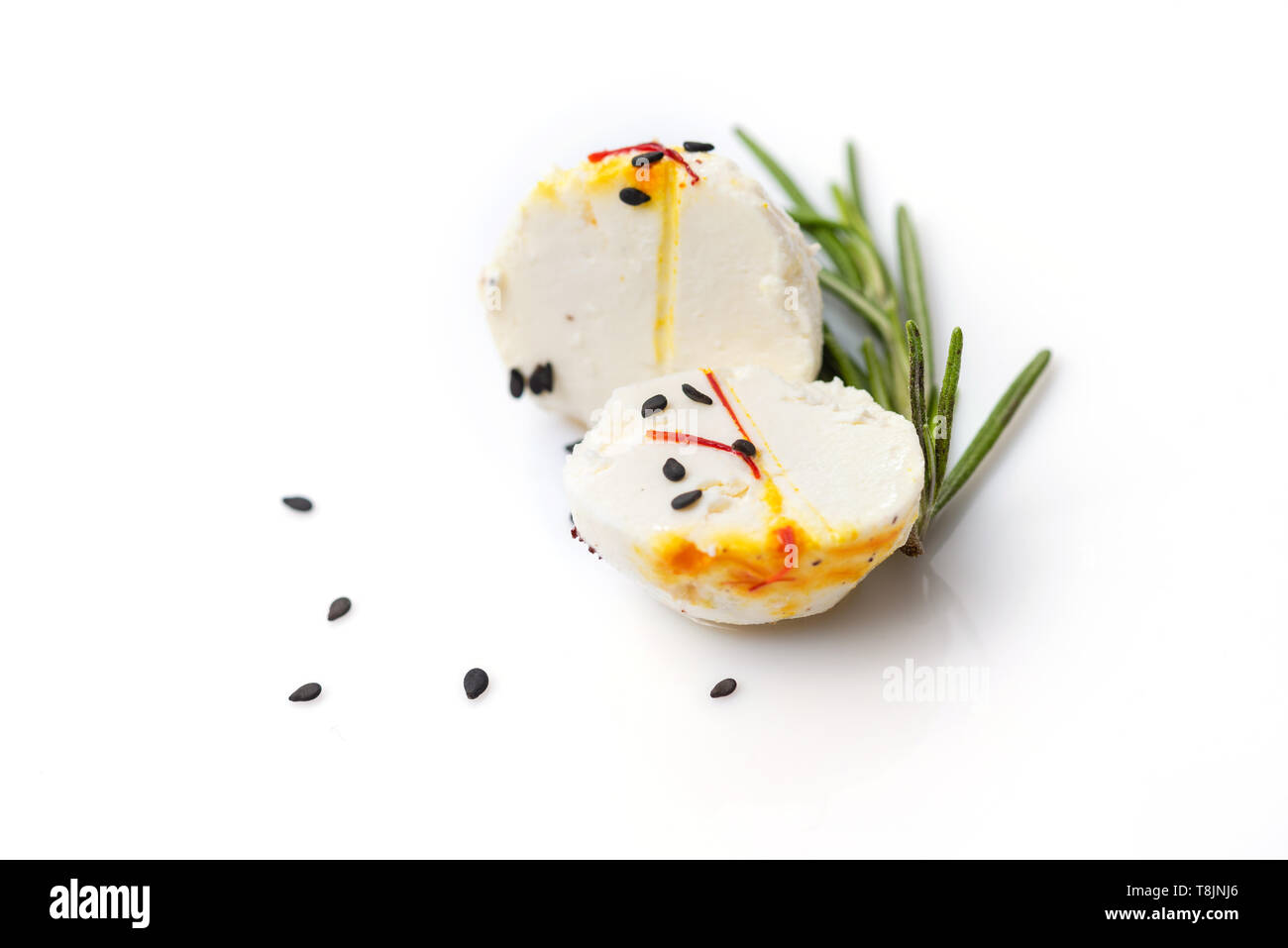 Two halves of cheese ball with sprig of thyme and sesame on white background. Stock Photo