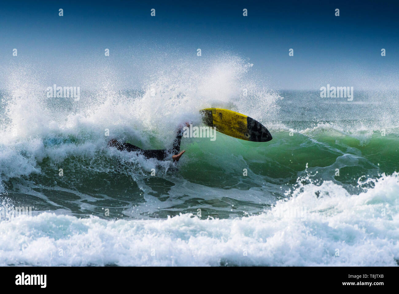 A surfer losing balance and wiping out on the crest of a wave at Fistral in Newquay in Cornwall. Stock Photo