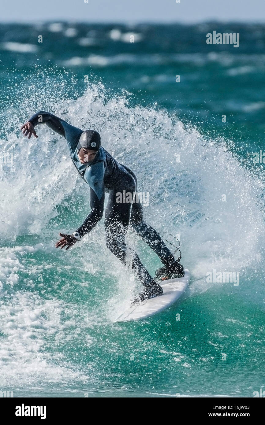 A surfer performs a snap trick on a wave at Fistral in Newquay in Cornwall. Stock Photo