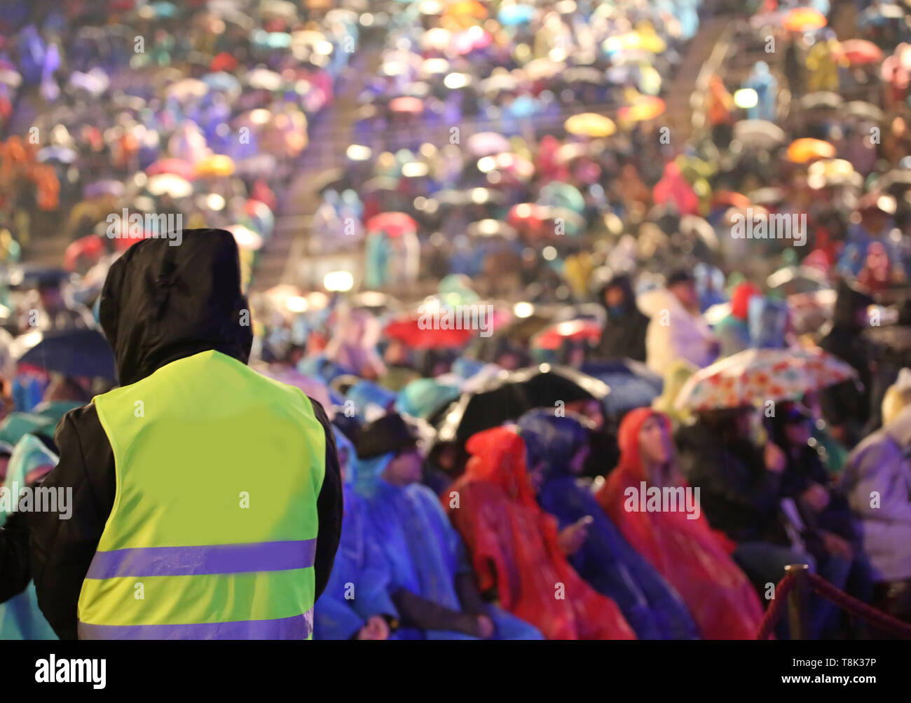 many people during a live event and a boy with jacket while raining ...