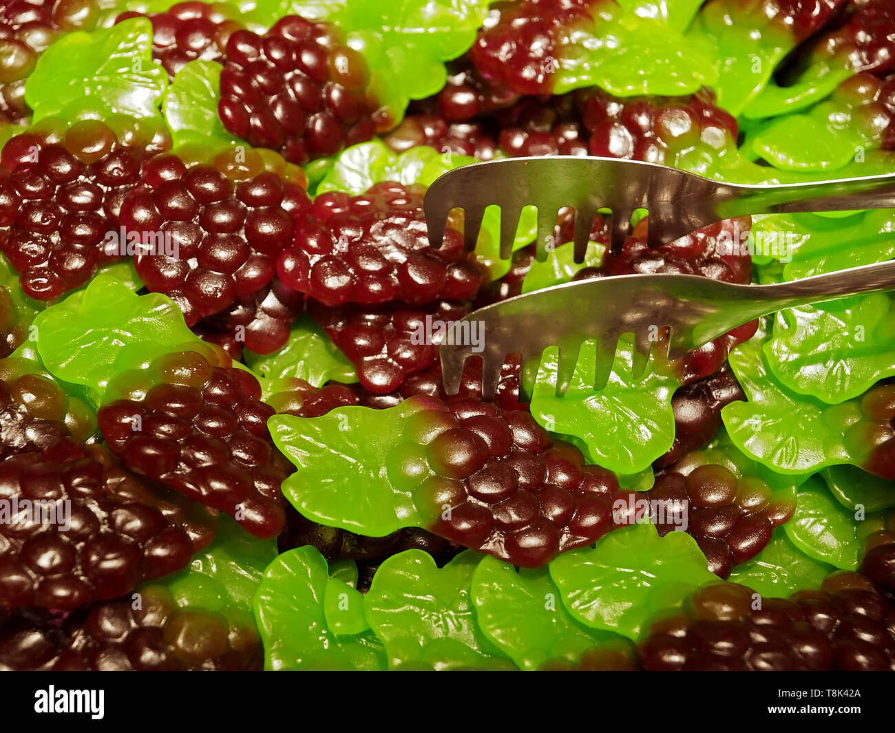 Pile of sweet and sour fruit gums, here wine grapes with a food pliers