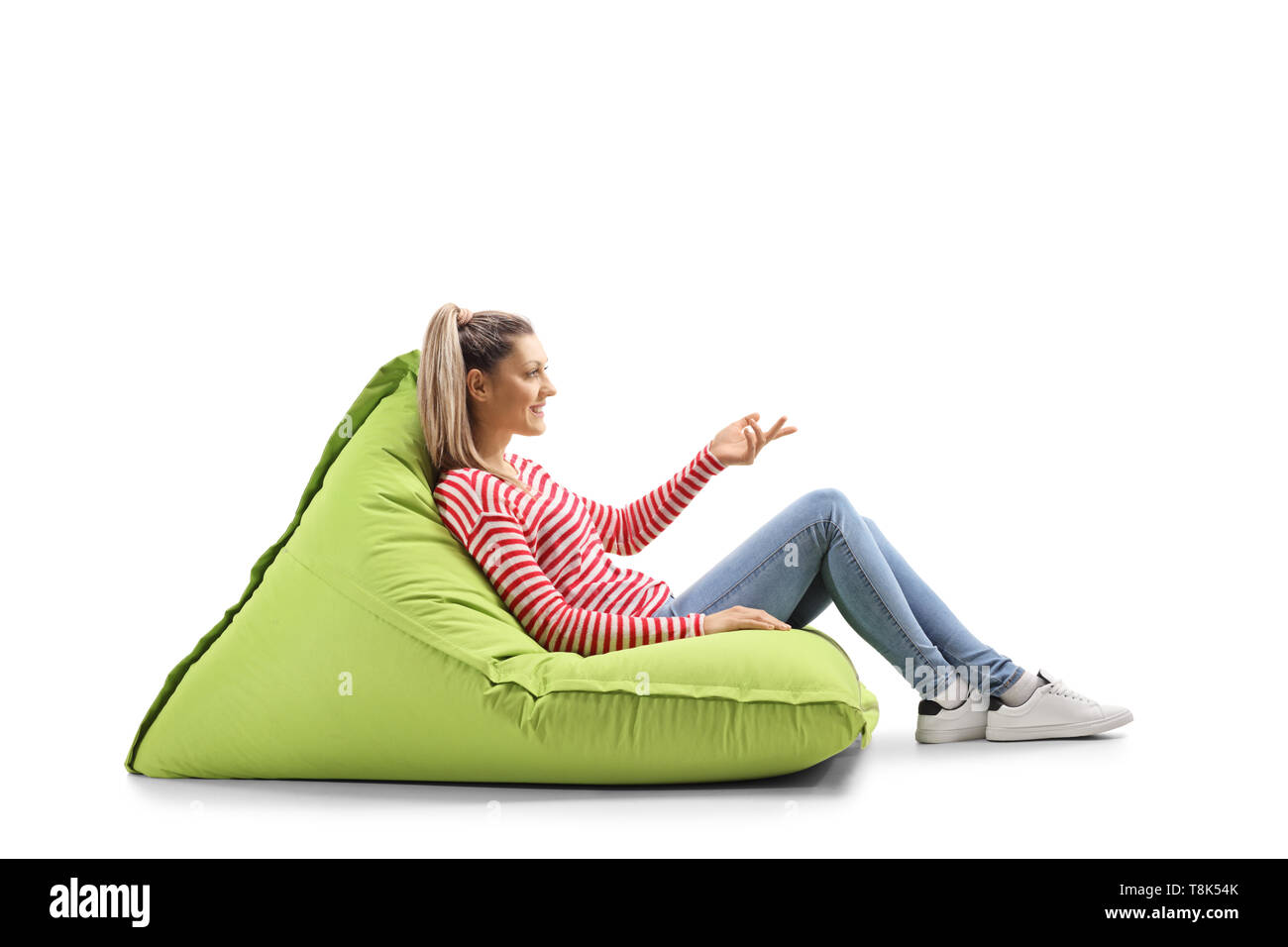 Full length profile shot of a young woman sitting on a bean bag and ...
