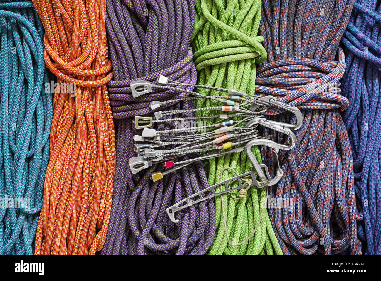 traditional rock climbing protection with used stoppers and nut tool and carabiners over a background of climbing ropes Stock Photo