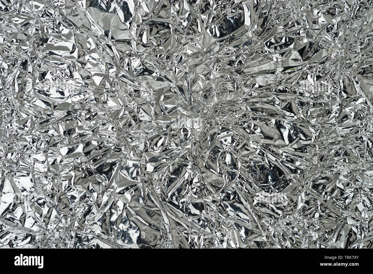 wrinkled and bent silver reflective metal foil background texture Stock Photo